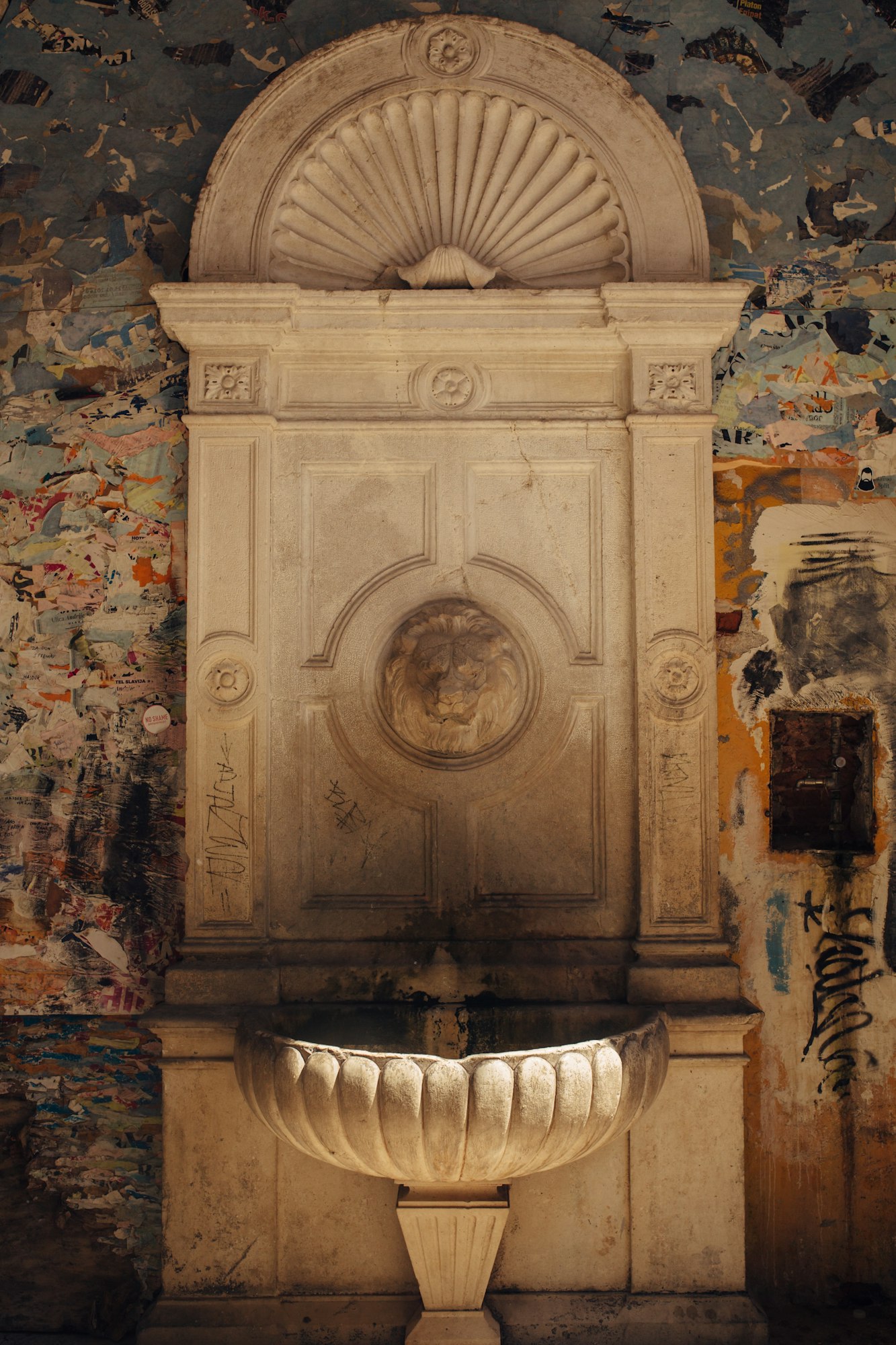 Old weathered drinking fountain with a sculpture of lion`s head