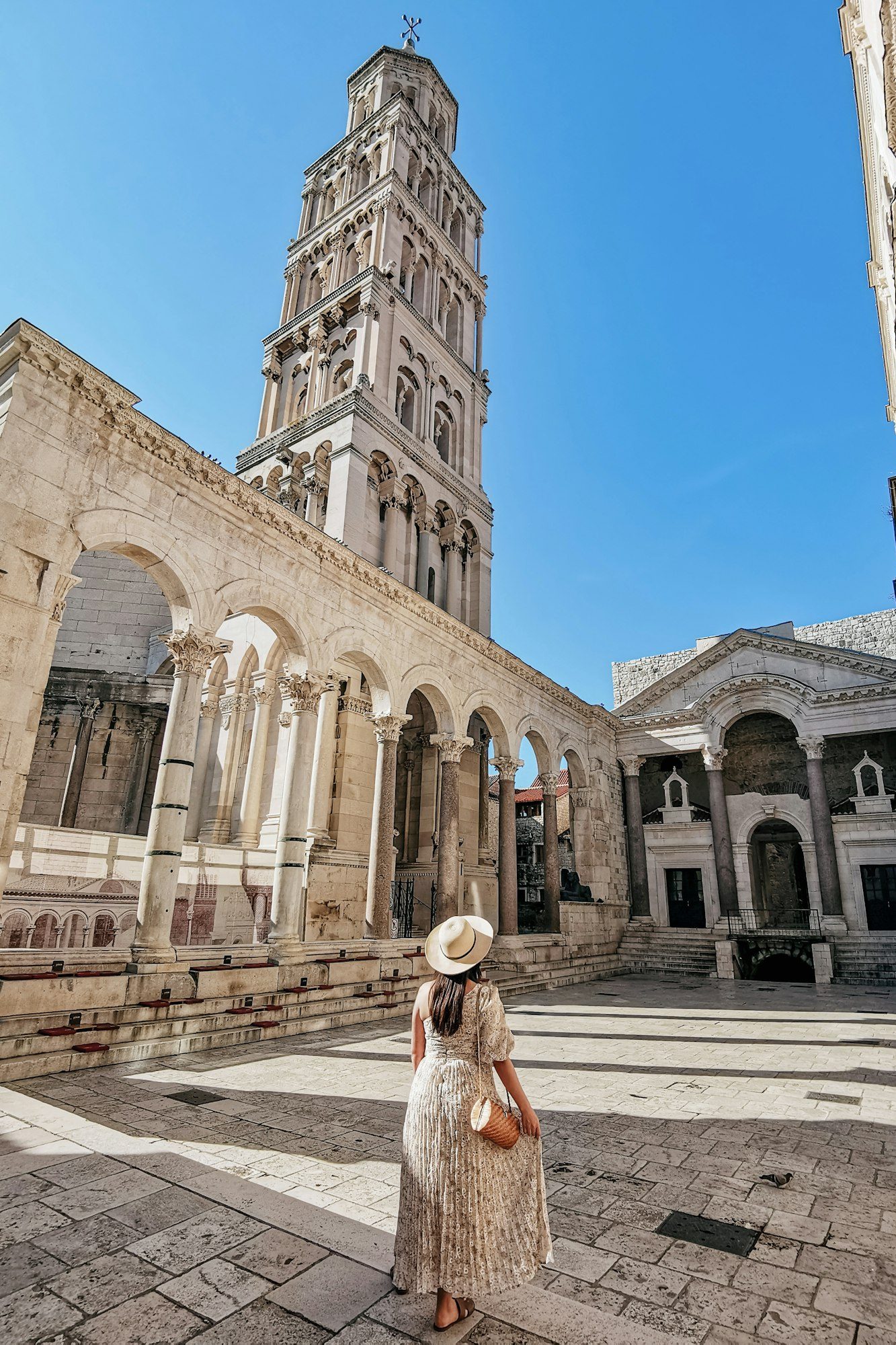 Woman in stylish summer dress standing in Peristyle of Diocletian's palace in Split, Croatia.